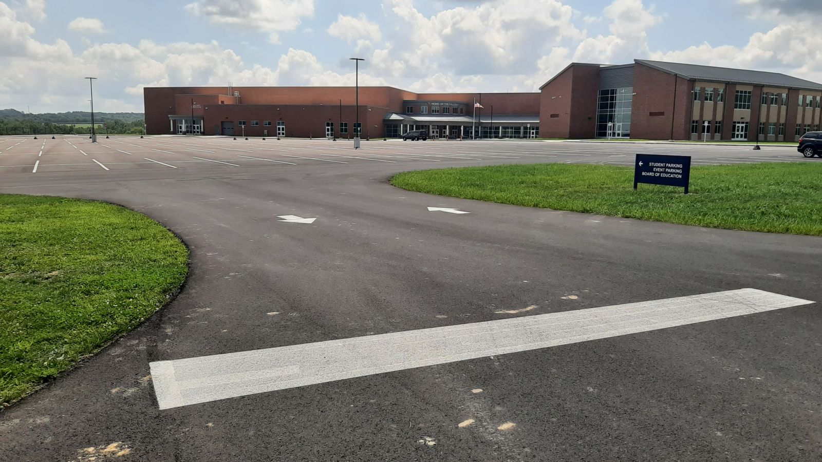An image of a two-way entrance and exit at the parking lot with correlating signage and painted lines on the blacktop. 