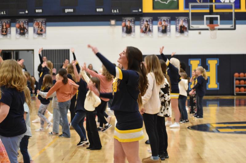 Students cheer from the gymnasium floor.