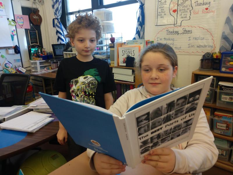 Two students look at their class book.