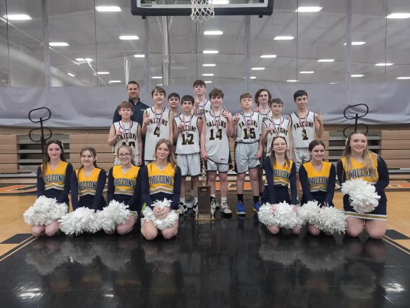 The boys' 7th-grade basketball team, coach, and cheerleaders pose for a group picture with their WCAL trophy.