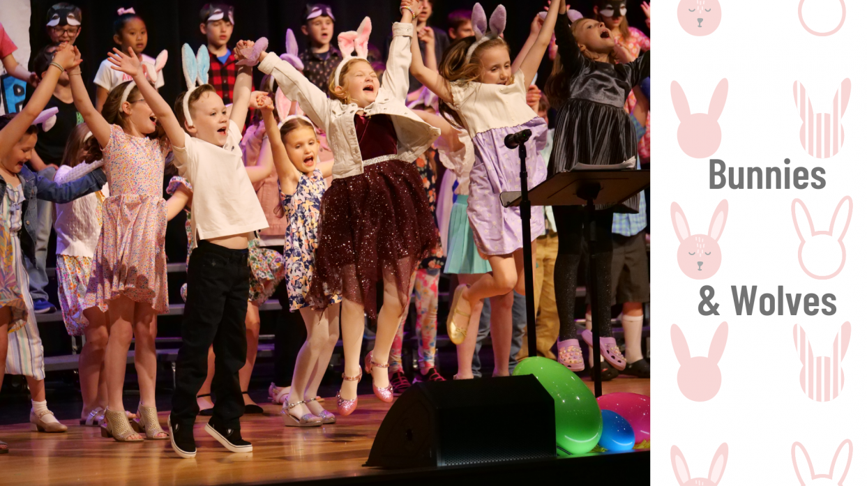 Students jump into the air with arms raised on stage during the 2nd-grade music program in April.