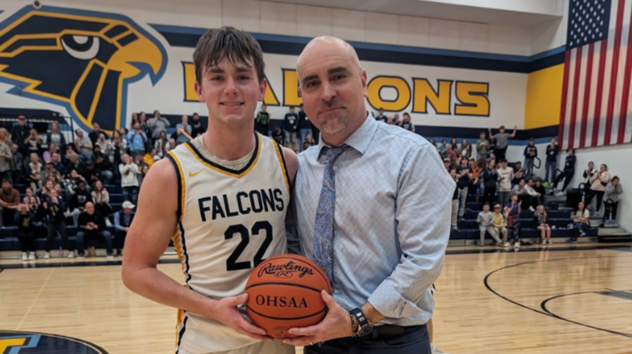 Braylen Jarvis and Coach Ben Ferguson pose for a photo holding a basketball after Jarvis scored his 1,000th career point.