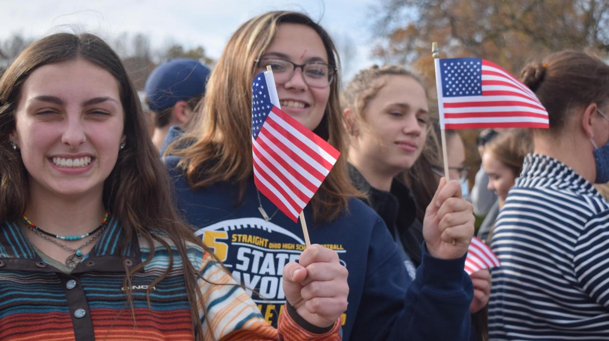Students hold small American flags.