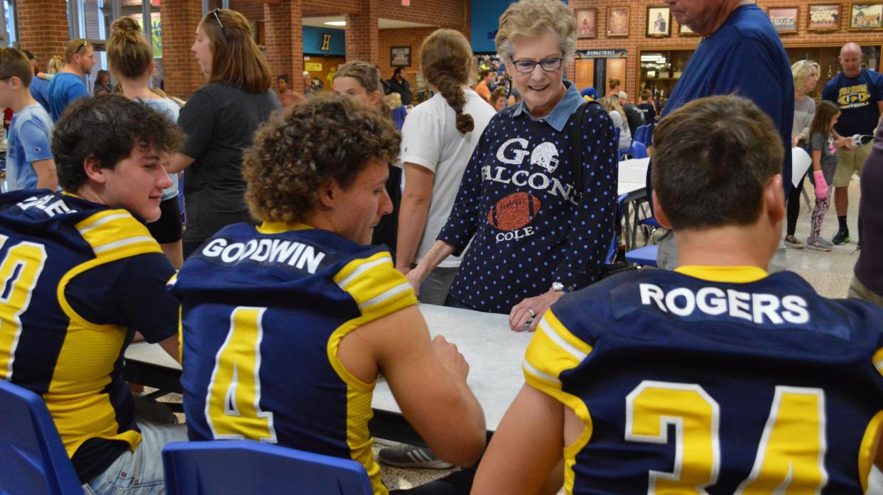 People stand in front of seated football players to collect autographs.