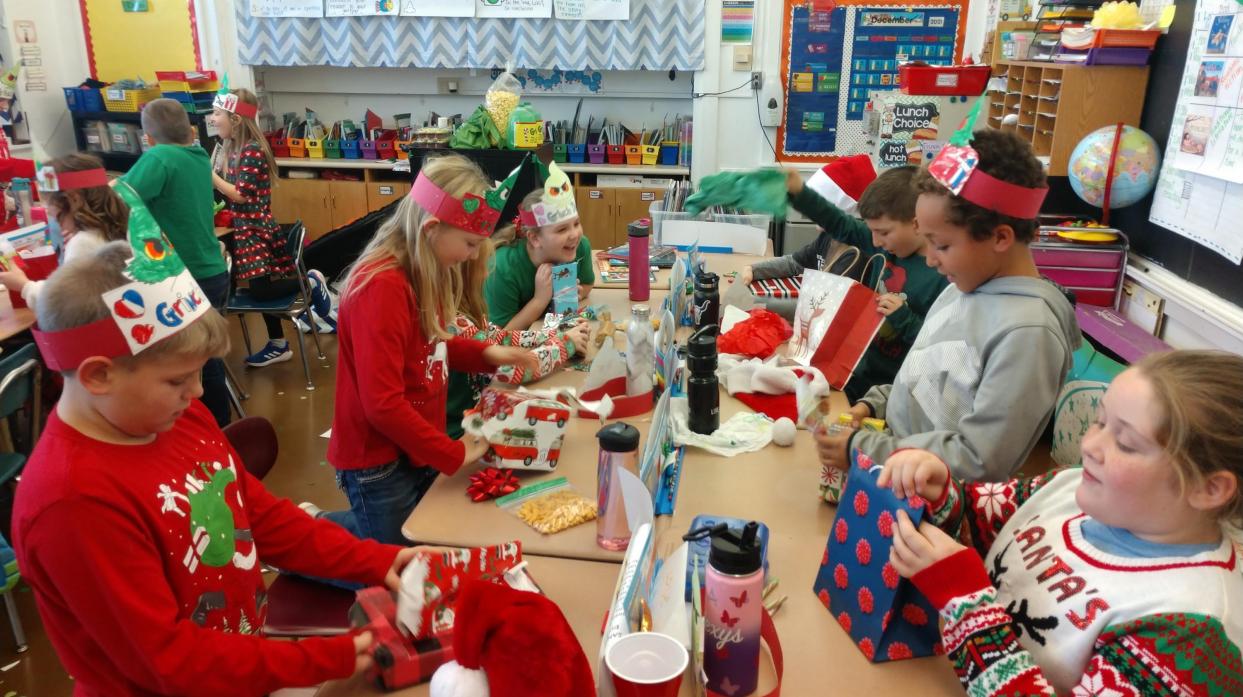 Students wearing self-made Grinch hats open presents.