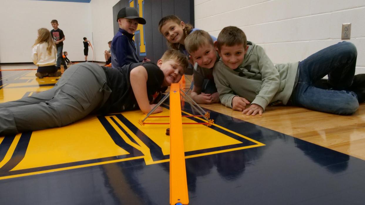 Students pose with a Hot Wheels track.