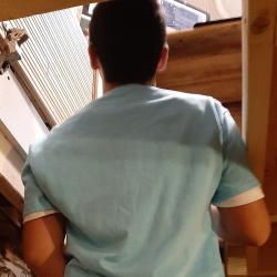 A photo of the back of a student standing on the metal stairs with his shoulders and head through the trap door in the ceiling