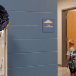 An image of students walking in the hallway with a sign with the text: "Welcome to your new school! We're glad YOU are here...Have a great first day!"
