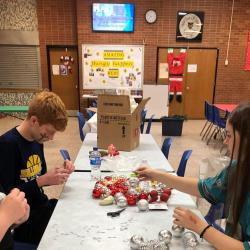 Students sit at a table with Christmas ornaments.