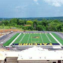 a drone shot from the back of the field house in the foreground and the football field in the background