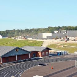 The end zone with "FALCONS" in the turf, the long jump and pole vault pits, the track with marked lanes and the field house are pictured.