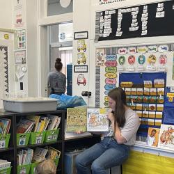 A high school student reads to elementary students.
