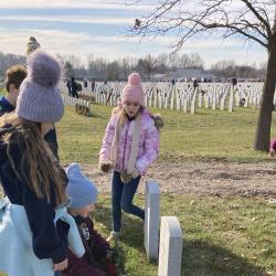 Students place a wreath on the gravesite of a U.S. Military service member.