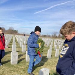 A student reads the inscription on a headstone at the gravesite of a U.S. Military service member.