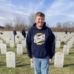 A student stands at the gravesite of a U.S. Military service member.