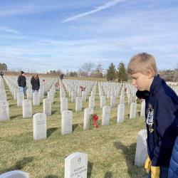 Students stand at the gravesite of a U.S. Military service member.