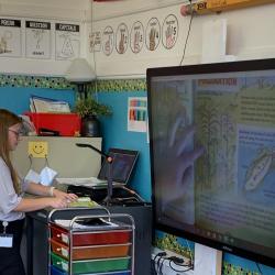 A high school student uses the document reader to project the book she's reading onto a screen.