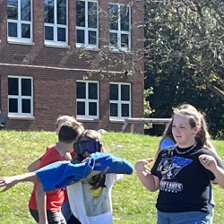 A student pulls on a shirt while wearing the goggles.