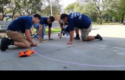 Students use a tape measure on a chalk circle to make a calculation.