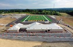 A drone photo of the field house from the back along with the retaining wall and the completed football field in the background