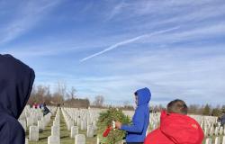 A student places a wreath on the gravesite of a U.S. Military service member.