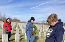 A student reads the inscription on a headstone at the gravesite of a U.S. Military service member.