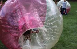 A student inside an inflatable ball rolls into an inverted position.