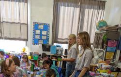 FFA members stand in the elementary classroom with students working on the craft.