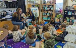 High school students read aloud to elementary students who follow along in copies of their own books.